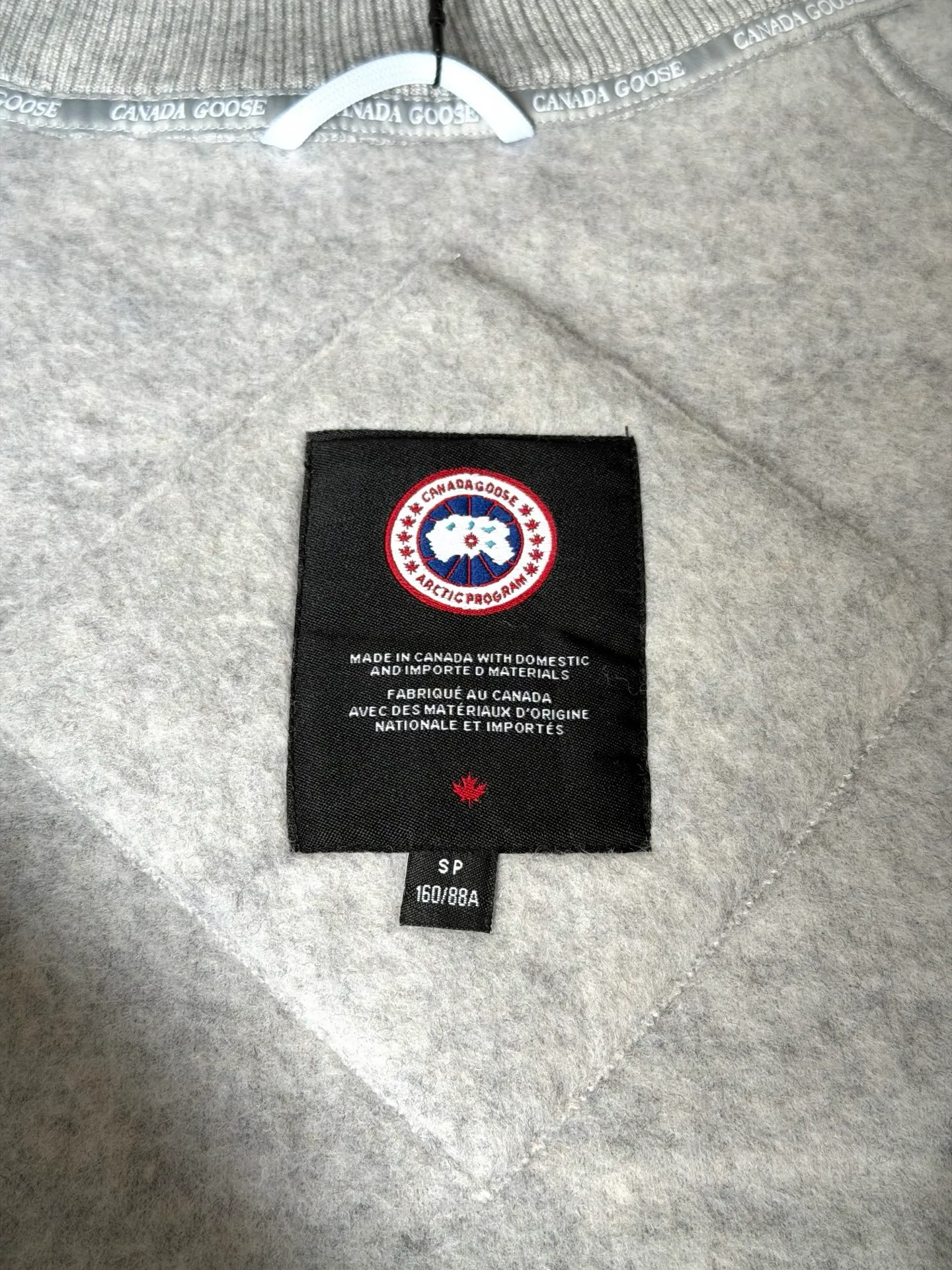 P620 Canada Goose Fleece Wool Baseball Jacket Fabric selection: Wool fleece fabric blended with wool as the main body and a very small amount of spandex and polyester fiber. Wool is a core natural ingredient that provides unparalleled temperature regulation, antibacterial and anti-odor properties and a skin-friendly feel. The feeding of a small amount of spandex gives the fabric a certain degree of four-way elasticity, making it non-restrictive during daily activities. As the basis of fleece's structure, polyester fiber enhances the fabric's durability, wrinkle resistance and quick-drying properties. It contributes to the loft of the fleece and provides functions such as trapping air.  Detail 1: The sleeves and hem are closed with 2×2 ribbing. Its strong elasticity can closely fit wrists and waists of different thicknesses, forming an effective 'seal' to prevent cold wind from blowing back. It can still maintain its original shape after repeated stretching and use, and is not easy to loose and deform. And the ribbed cuffs can convey a sense of design and enhance the visual beauty.  Detail 2: The combination of hood design and elastic buckle improves warmth and windproof performance when wearing. Accessories: Customized elastic drawstring, elastic buckle, custom zipper pendant, custom armband Size: S M L Color: Black Gray Mickey